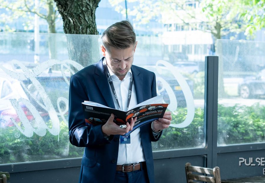 A delegate reading the printed programme beside a window at a previous Excellence in Digital Banking summit